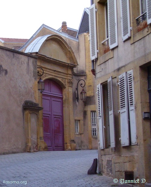 Grande
                porte de bois peint mauve dans le coude d’une ruelle ( Rue
                de la Princesserie à Metz )
            
